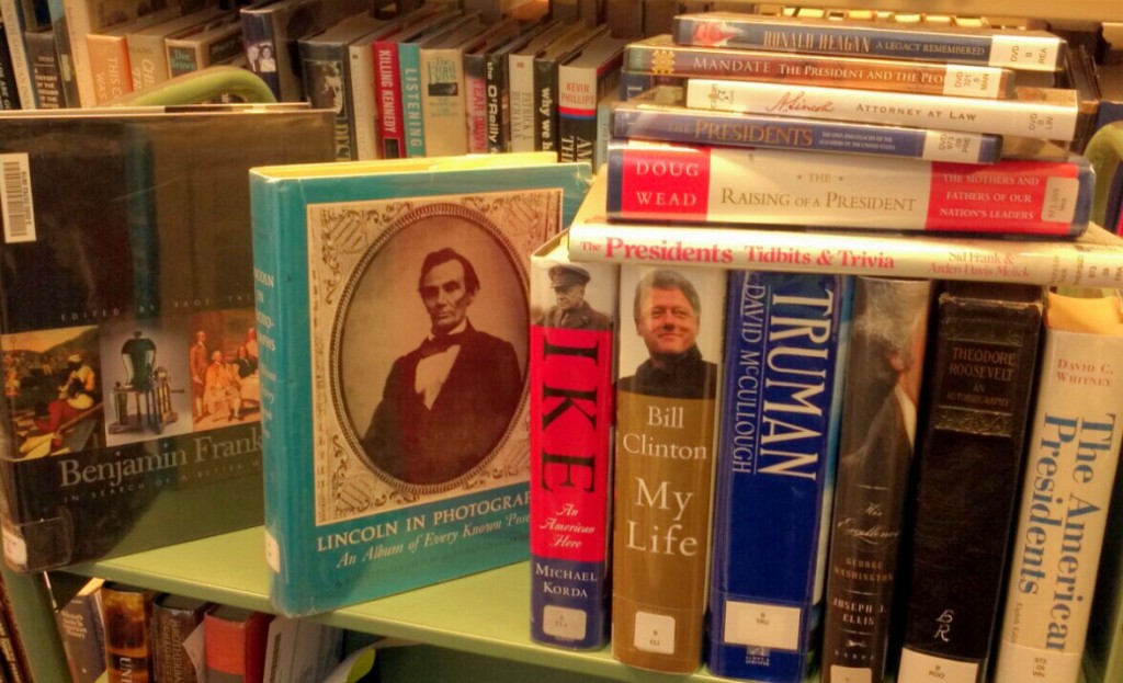 Photograph of numerous books stacked on a book cart concerning all things "Presidential"