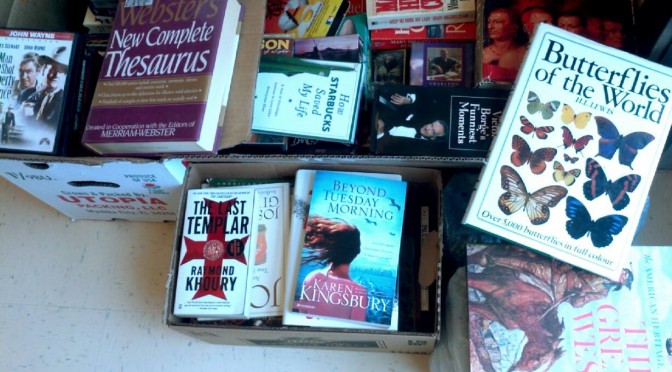 A photograph of several boxes of donated books setting on the floor by the side entrance of the library.