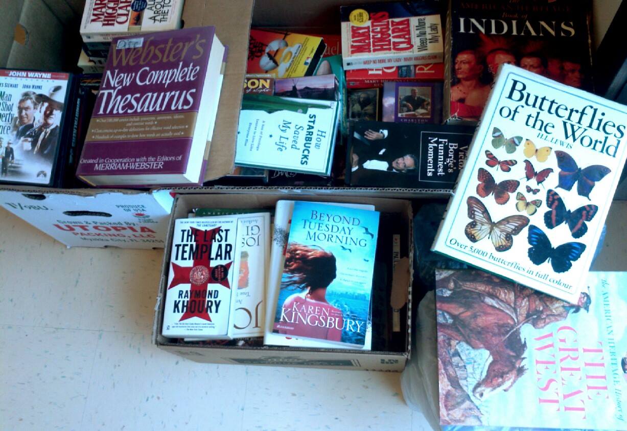A photograph of several boxes of donated books setting on the floor by the side entrance of the library.